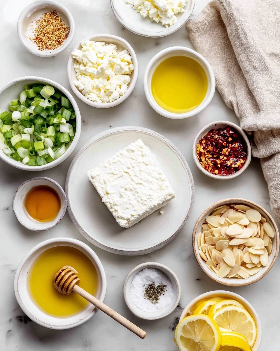 The image shows a white marbled surface with several small white bowls arranged neatly. There is a block of white cheese on a white dish near the center. Surrounding it are bowls containing chopped green onions, minced garlic, a thick white creamy ingredient, yellow lemon juice, red chili flakes, olive oil, and honey with a honey dipper resting inside. There are also lemon slices stacked at the bottom right, a small bowl with salt and pepper mix, and a bowl filled with sliced almonds. A folded beige cloth is placed near the top right edge. The setting is bright and clean, and the bowls are evenly spaced. Photo taken with an iphone --ar 4:5 --v 7