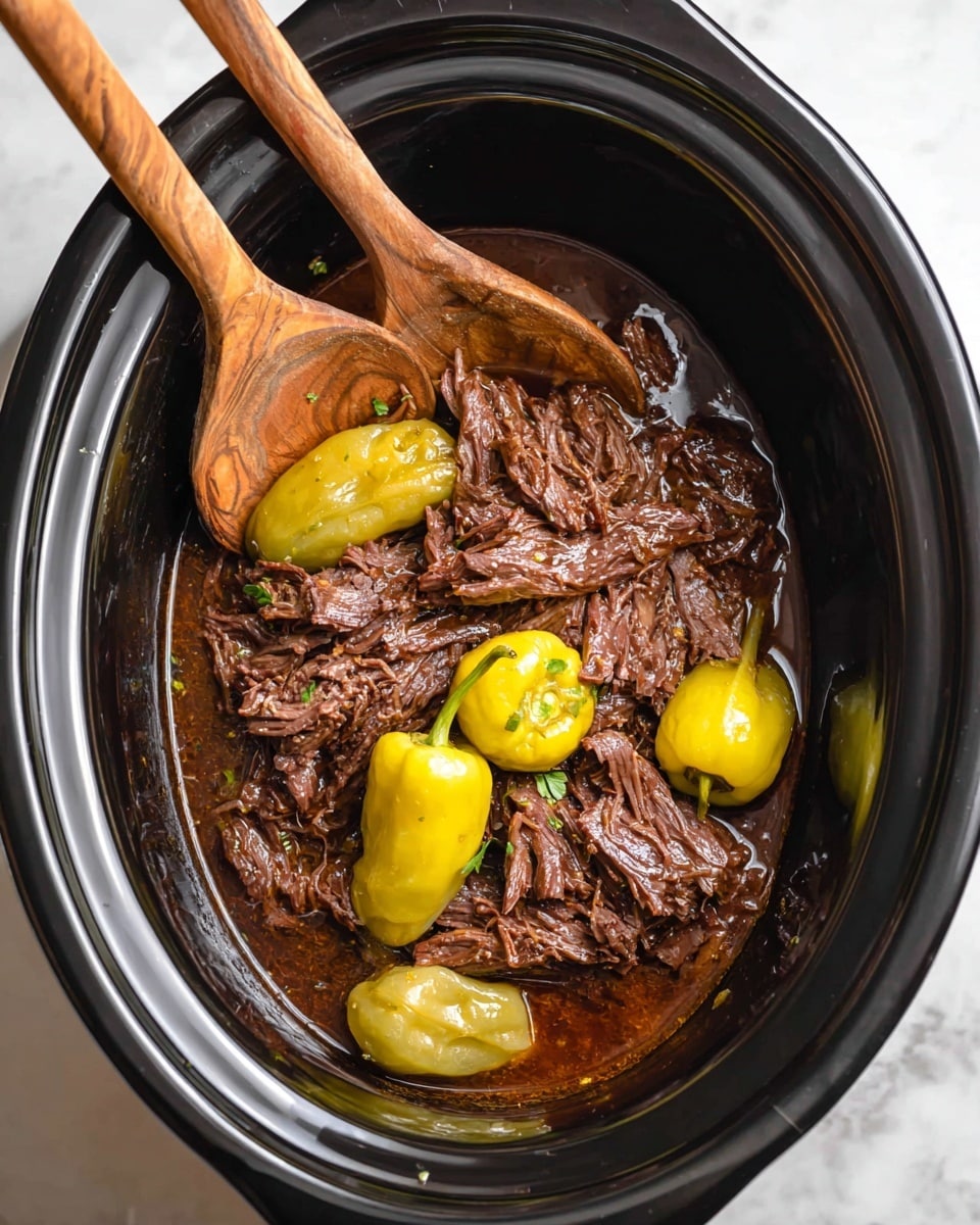 Inside a black slow cooker, there is one main layer of shredded dark brown cooked beef in a rich brown sauce. Scattered on top and around the beef are several whole yellow and light green peppers with smooth, slightly shiny skin. Two wooden spoons rest on the beef, showing their natural wood grain textures. The slow cooker sits on a white marbled surface. photo taken with an iphone --ar 4:5 --v 7