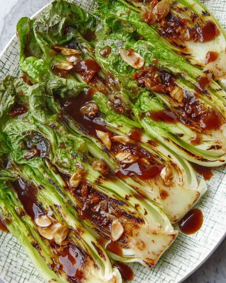 The dish shows several green grilled romaine lettuce halves arranged closely on a white plate with a patterned surface. Each lettuce half is charred lightly with brown grill marks, and they are topped with thinly sliced golden-brown garlic pieces. A shiny, dark brown sauce is drizzled over the lettuce, pooling in some areas and adding a glossy texture. The plate sits on a white marbled surface. photo taken with an iphone --ar 4:5 --v 7