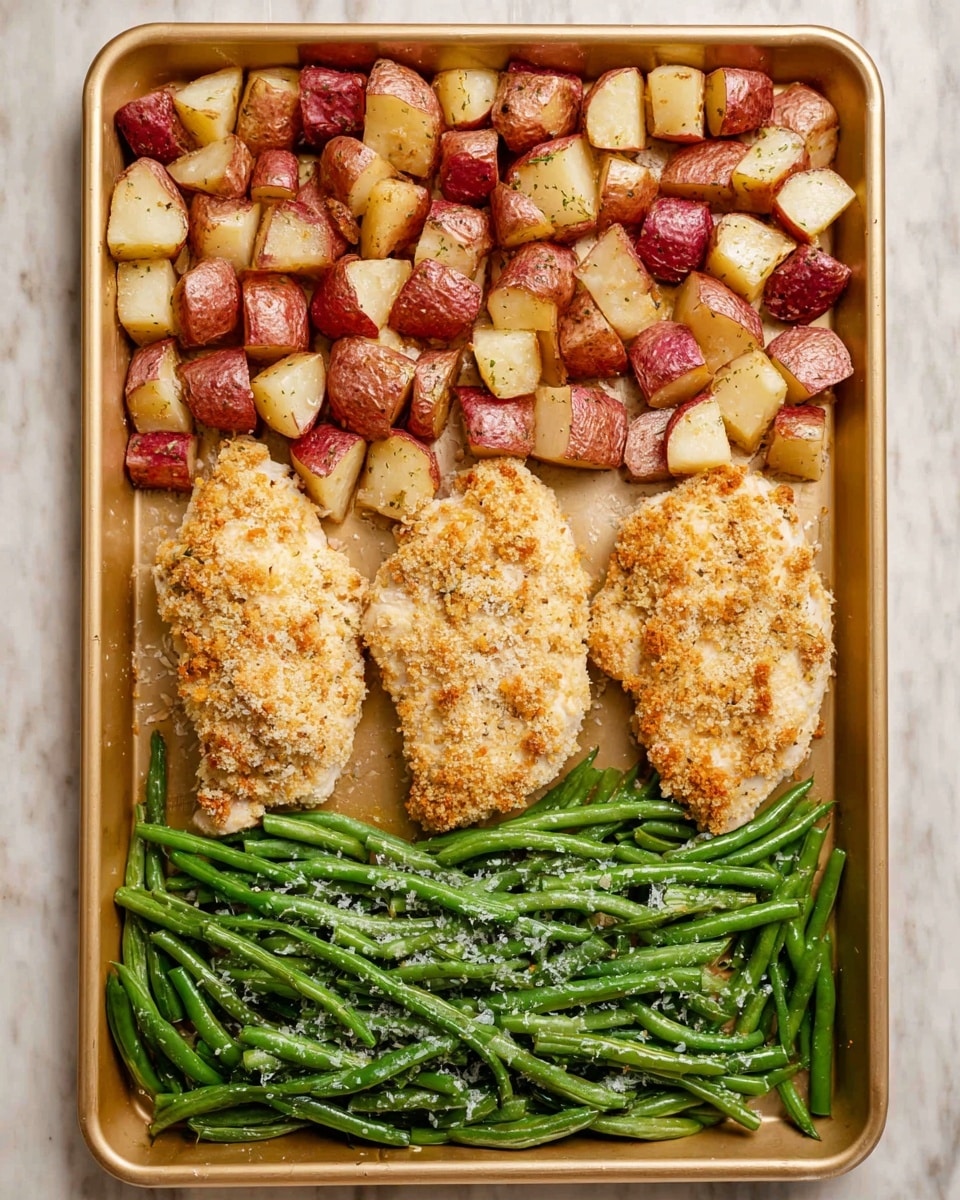 The image shows a gold baking tray filled with three sections of food arranged neatly in rows. At the top, there is a layer of small, cubed red potatoes with skin on, roasted to a light golden brown and showing some crispy edges. In the middle, three pieces of chicken covered in a crumbly, light golden crust are placed side by side, each with a slightly rough texture from the coating. At the bottom, there is a layer of bright green beans scattered with flakes of coarse salt, appearing fresh and slightly glossy. The tray sits on a white marbled surface. photo taken with an iphone --ar 4:5 --v 7