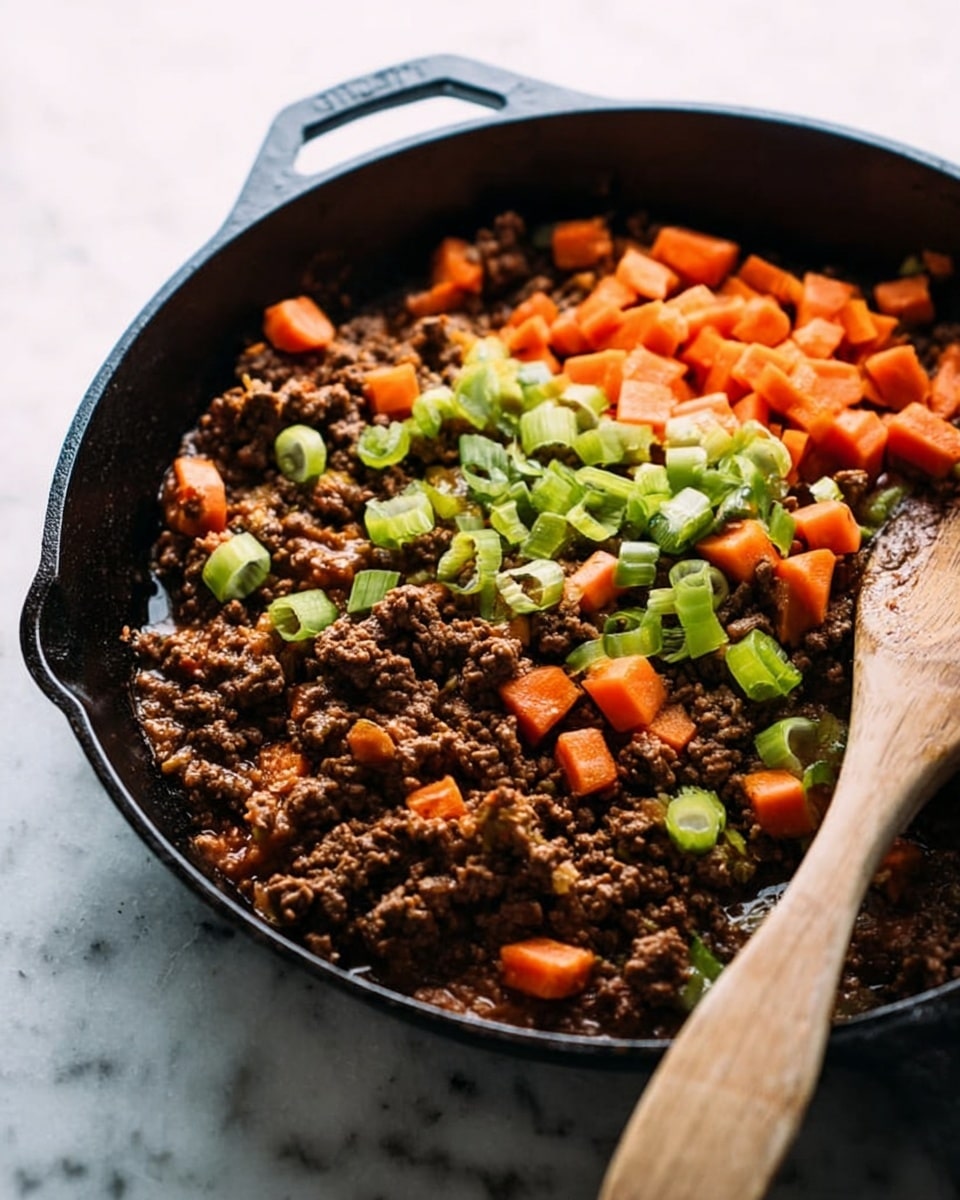 A black cast-iron pan filled with cooked ground meat forming the bottom layer, dark brown and crumbly in texture. On top, there are scattered bright orange carrot chunks and pale green sliced celery, with some green rings of leek adding contrast. A wooden spoon with a smooth, natural brown texture is resting inside the pan on the right side. The pan sits on a white marbled surface with soft natural light coming from the left side, highlighting the colors and textures. Photo taken with an iphone --ar 4:5 --v 7