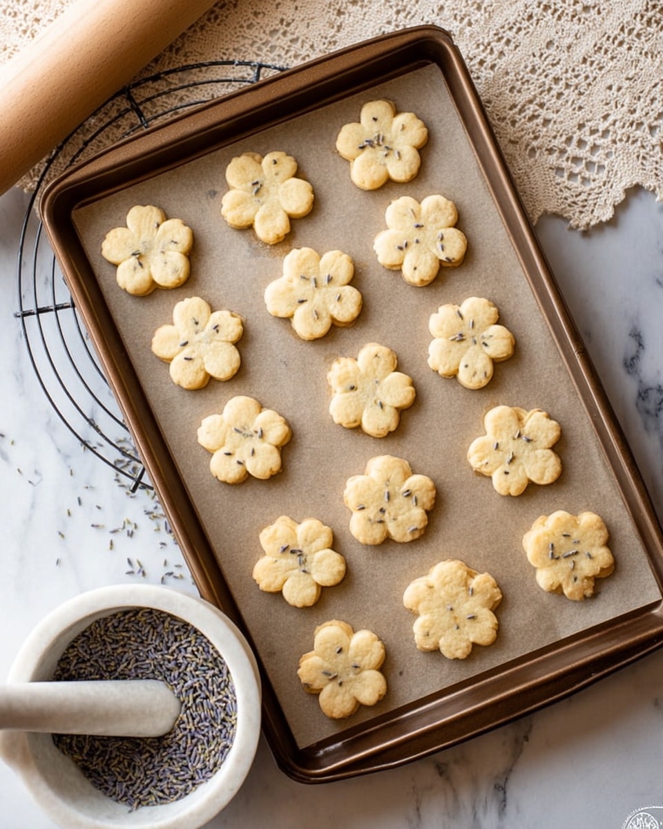 There is a stack of ten light beige cookies shaped like flowers with small bits inside, arranged on a white plate with detailed blue floral patterns. The plate sits on a round white marble surface. In the background, slightly out of focus, there is a white marble mortar and pestle with dark contents inside it and a wooden rolling pin resting on a white cloth. The overall scene is bright with soft natural light. Photo taken with an iphone --ar 4:5 --v 7