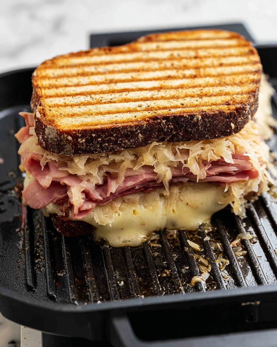 The image shows a toasted sandwich being grilled with two dark brown slices of bread that have visible grill lines on the top slice. Inside, there are multiple layers: a bottom layer of melted cheese bubbling slightly out at the edges, a middle layer of folded pink ham with a slightly crispy edge, and a top layer of sauerkraut mixed with melted cheese visible from the sides. The sandwich is on a black grill pan with melted ingredients oozing and some liquid pooling underneath. The background surface is white marbled texture. Photo taken with an iphone --ar 4:5 --v 7
