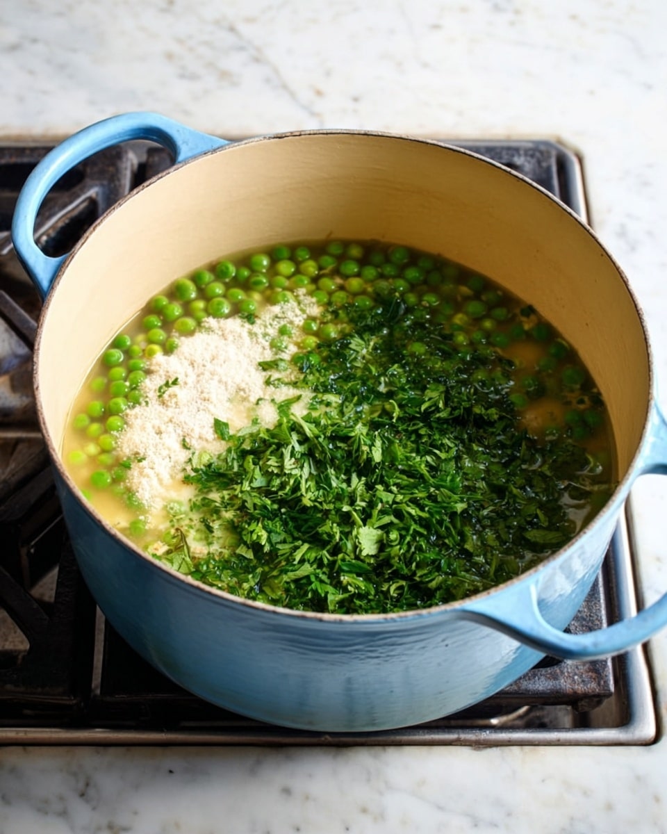 A light blue pot filled with bright green peas in clear broth sits on a stove. On top of the peas, there is a white powdery layer on the left side and fresh, chopped dark green herbs spread over the right side. The inside of the pot is a light cream color, and the pot handles are visible on both sides. The surface around the stove is a white marbled texture. photo taken with an iphone --ar 4:5 --v 7