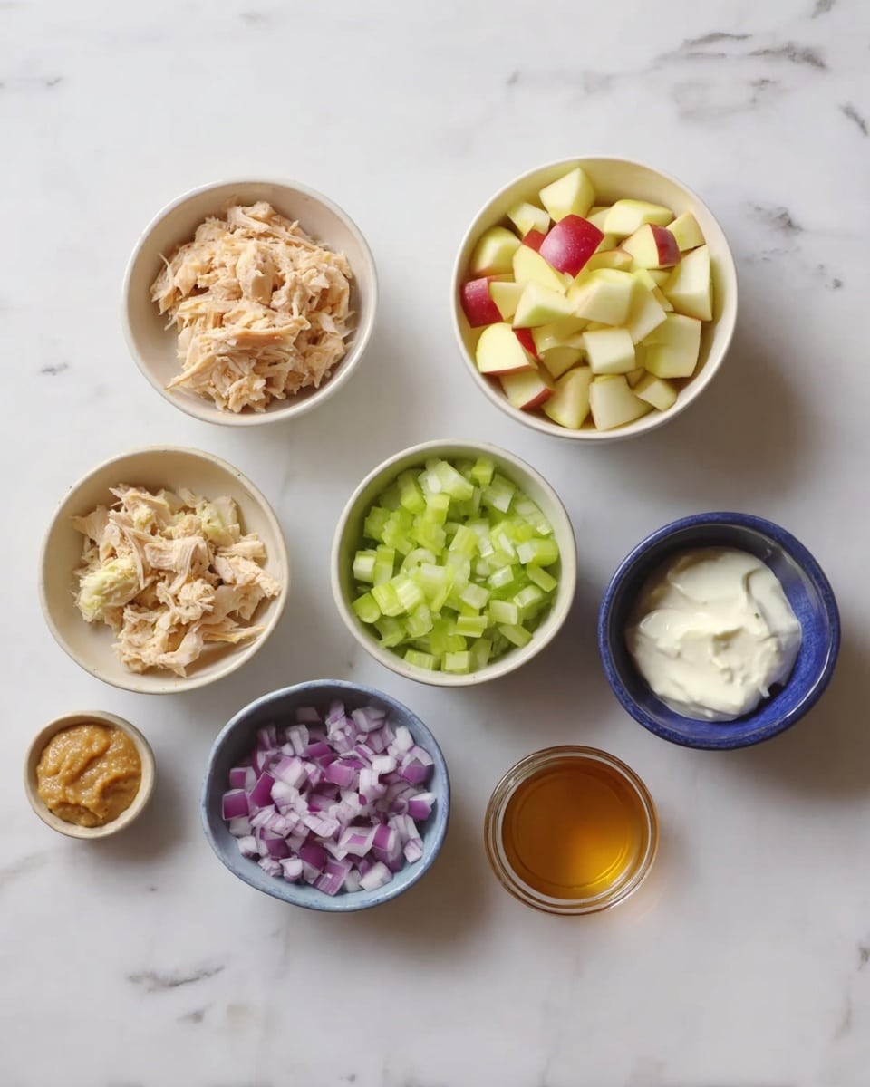 The image shows seven small white bowls on a white marbled surface, each with a different ingredient. At the bottom left, a bowl holds light brown shredded chicken. Above it, a bowl contains light green chopped celery. To the right of the celery, a bowl is filled with small pale yellow and red apple pieces. Below the apples, a bowl has small purple chopped onions. In the center bottom, a bowl contains white creamy mayo. To its right, a small glass bowl has a light amber liquid, likely honey or vinegar. Above the mayo, a small blue bowl holds a light brown paste, possibly mustard or ginger paste. photo taken with an iphone --ar 4:5 --v 7