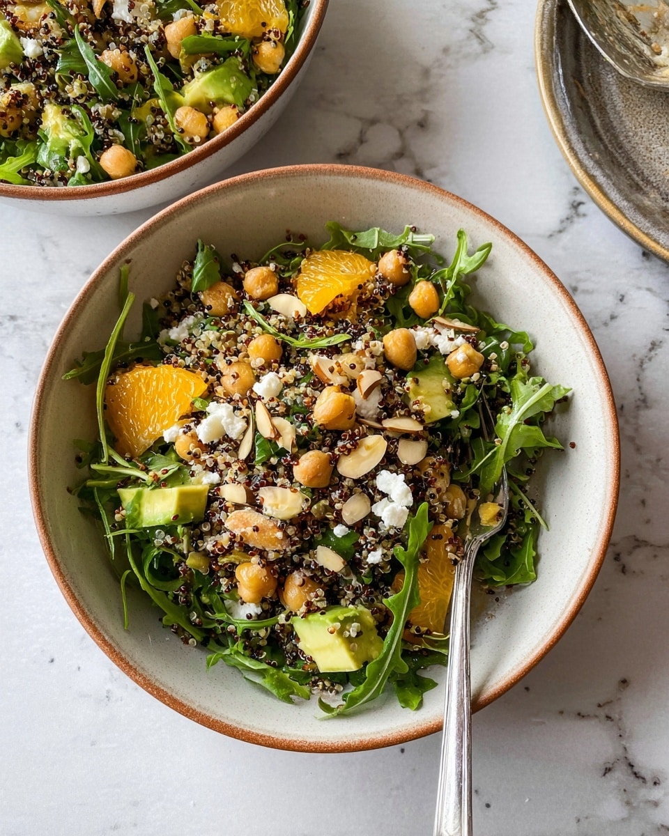 The image shows a large wooden bowl filled with a colorful salad made of several layers. The bottom layer is dark green arugula leaves mixed with cooked quinoa, which adds a grainy texture with small red and white seeds scattered throughout. On top, there are bright orange slices of oranges arranged evenly, giving a pop of color. Large chunks of green avocado cubes are spread across the salad. Light beige chickpeas are scattered all over. Small white pieces of soft cheese sit on top, with thin light brown almond slices sprinkled around. There is a pale white spoon partially visible in the bowl on the right side. The bowl is placed on a white marbled surface. Photo taken with an iphone --ar 4:5 --v 7