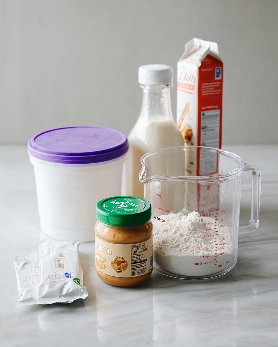 The image shows a clear measuring cup filled with white powder placed on a white marbled surface. In front of the cup, there is a jar of peanut butter with a green lid and a light beige label, along with a white packet lying flat. To the left of the measuring cup, a white tub of yogurt with a purple lid stands with a small bottle containing a creamy white liquid resting on top. Behind them, a carton of milk with red and white packaging leans against the wall. The background is light and plain, adding to the clean look of the arrangement. photo taken with an iphone --ar 4:5 --v 7