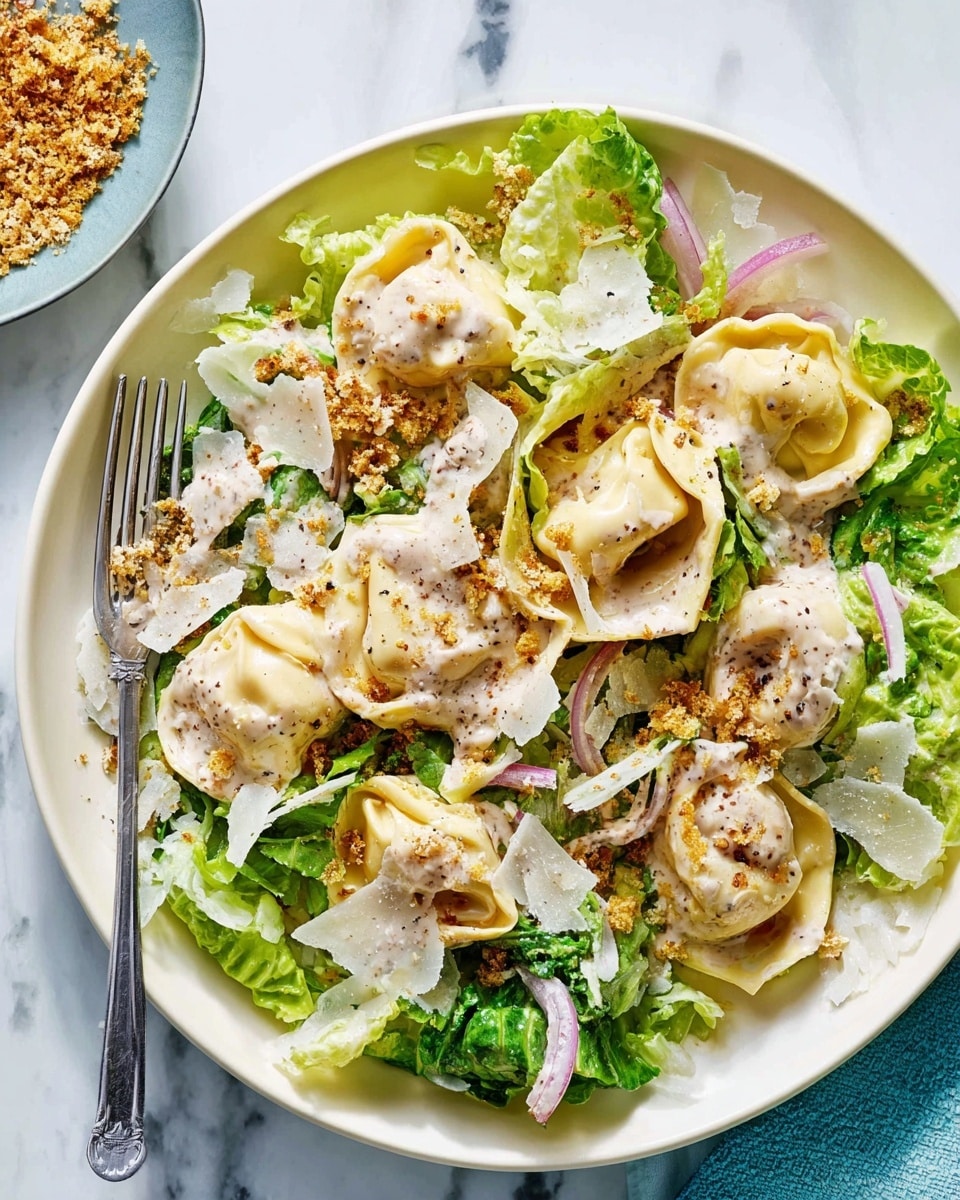 The dish shows a white plate filled with fresh green lettuce leaves forming the base layer, mixed with thin slices of light purple onion scattered throughout. On top, there are several folded pale yellow tortellini pasta pieces coated in a creamy, light beige sauce. Thin, irregular white cheese shavings are spread over the lettuce and pasta, along with a sprinkling of golden-brown crispy crumbs for texture. The background is a white marbled surface, and a fork rests in the plate on the left side. Photo taken with an iphone --ar 4:5 --v 7