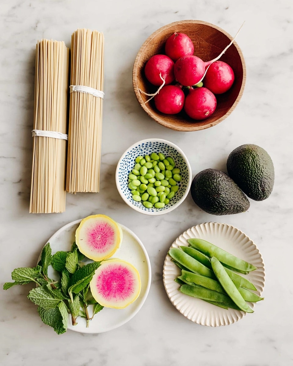 The image shows ingredients neatly arranged on a white marbled surface. On the left, there are two bundles of light beige dried noodles tied with white bands, and below them is a small white bowl filled with bright green edamame beans. In the center are two dark green avocados with a bumpy texture. At the top middle, a wooden bowl holds four round, bright red radishes with short green stems. To the right of the radishes is a small white plate with blue dots around the edge, holding fresh green mint leaves. Below the mint plate, there are two slices of watermelon radish showing a yellow outer layer and a pink center with white streaks. At the bottom right is a small white bowl with a scalloped edge, filled with fresh, crisp green snap peas. photo taken with an iphone --ar 4:5 --v 7