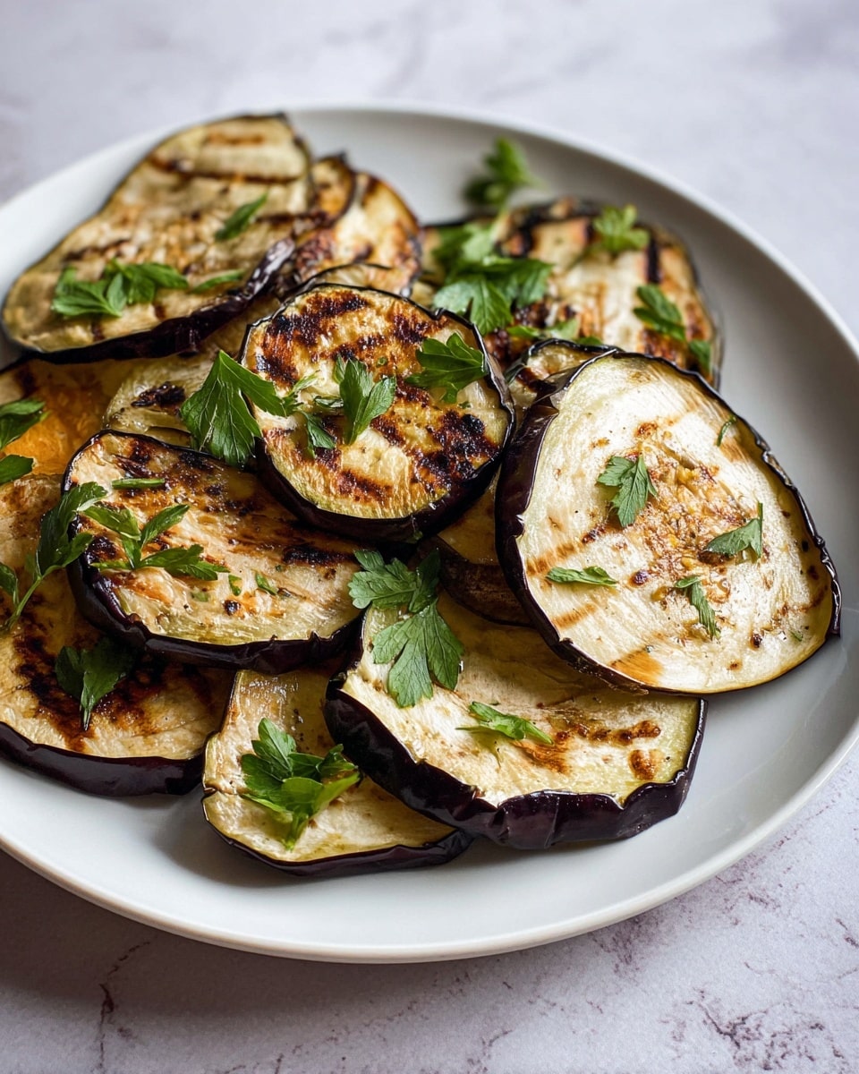 A white plate holds several grilled eggplant slices layered unevenly, showing their light golden, slightly browned texture with thin dark edges. The eggplants have a mix of smooth and wrinkled skin with darker spots where they were grilled. Scattered on top are fresh green parsley leaves, adding contrast to the mostly beige and brown tones of the eggplant. The plate sits on a white marbled surface, giving a clean and simple look. photo taken with an iphone --ar 4:5 --v 7