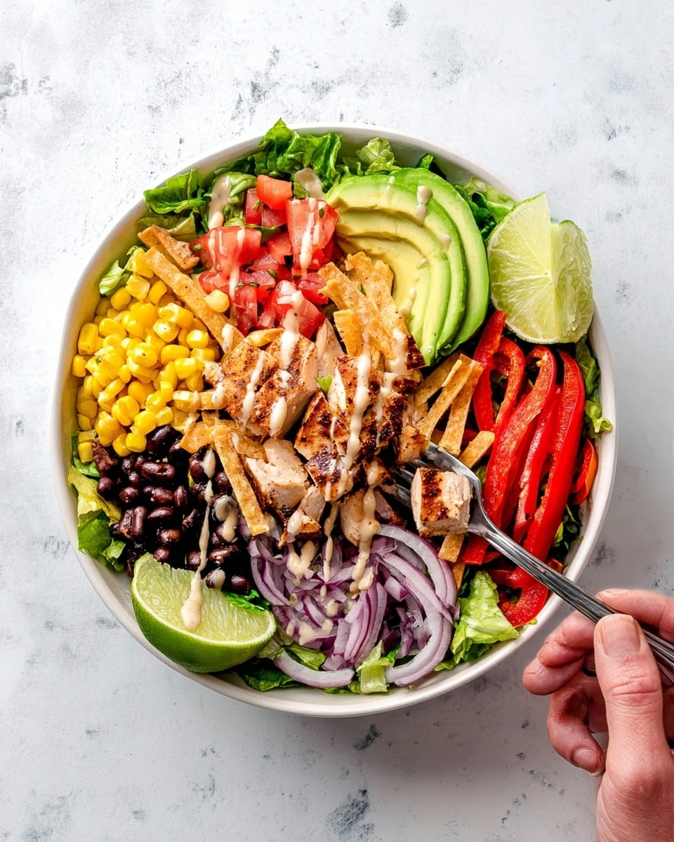 A white bowl filled with a colorful layered salad placed on a white marbled surface. The bottom layer is green leafy lettuce covering the whole bowl. On top, layers are arranged in sections: yellow corn kernels at the bottom left, black beans next to the corn, grilled chicken pieces with light brown grill marks in the center, red diced tomatoes to the top left, sliced avocado half with light green creamy texture at the upper middle, thin crispy tortilla strips over the avocado and chicken, finely sliced red onion rings on the upper right, and bright red bell pepper strips at the right side of the bowl. A light creamy dressing is drizzled over the avocado, chicken, and tomato. Two fresh lime slices rest at the edge of the bowl near the corn. A woman's hand holding a fork is seen lifting some pieces of chicken and red bell pepper from the bowl. Photo taken with an iphone --ar 4:5 --v 7