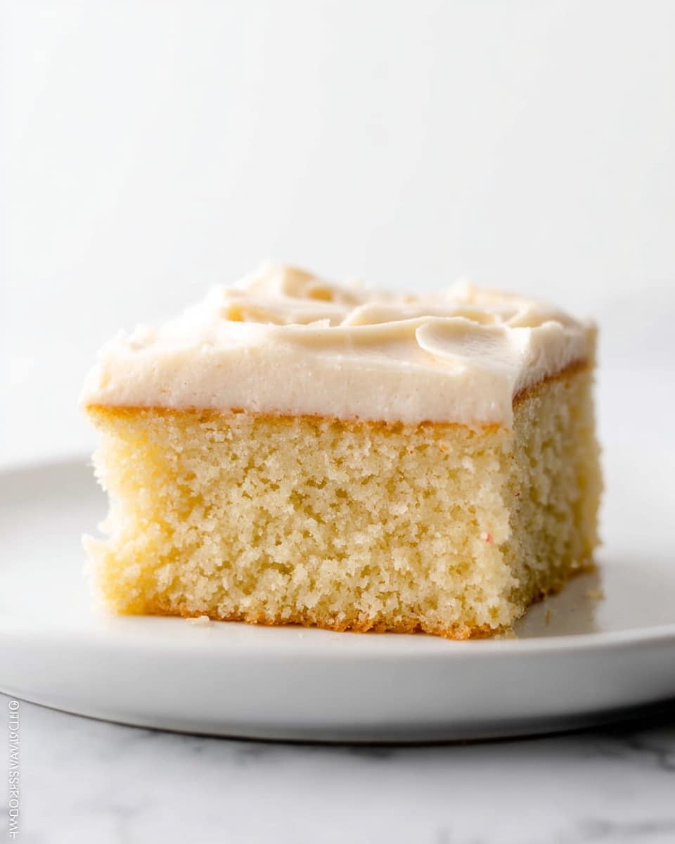 A close-up of a single-layer vanilla cake cut into squares in a clear glass pan, showing a thick, soft, light brown cake base topped with a smooth, creamy white frosting. The frosting layer is thick, slightly whipped in texture, covering the entire top of each square, and is decorated with small, colorful sprinkles in pink, green, orange, blue, and white, spread unevenly. The cake is sitting on a white marbled surface, with one square lifted slightly to reveal the cake's soft crumb inside. The edges of the cake are slightly darker, indicating a baked crust. photo taken with an iphone --ar 4:5 --v 7