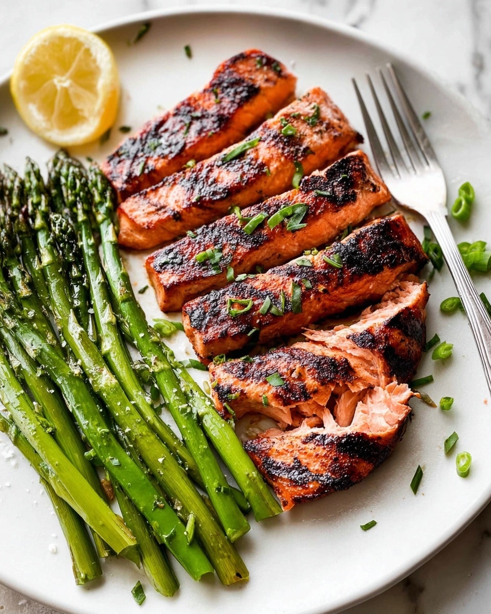 A white plate on a white marbled surface holds a dish with two main parts: on the left, seven thick slices of grilled salmon lay side by side, each slice showing a light orange-pink interior with dark charred grill marks on top, sprinkled with small green herb leaves; on the right, a neat bunch of bright green asparagus spears runs parallel to the salmon, topped with a light sprinkle of coarse salt. In the top left corner of the plate, there is a pale yellow lemon wedge, and a silver fork rests at the bottom right edge of the plate with some green scallion pieces scattered nearby. photo taken with an iphone --ar 4:5 --v 7