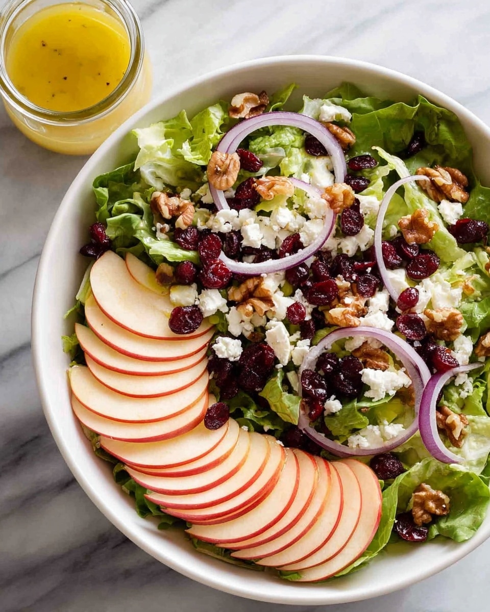 A white bowl filled with a fresh salad shows three main layers: at the bottom are green leafy vegetables with different shapes and shades of green, in the middle are thin slices of red apple with smooth skin and white flesh, and on top are pieces of brown walnuts, small dark dried berries, and crumbles of white cheese scattered throughout. Two golden forks held by a woman's hand are lifting some salad from the bowl, mixing the ingredients together. All this sits on a white marbled surface photo taken with an iphone --ar 4:5 --v 7