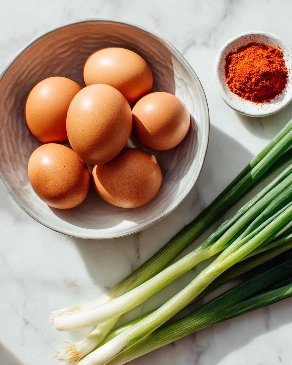 A round white bowl holds five brown eggs with smooth shells, arranged close together inside. Next to the bowl on the right are several green onions with long green stalks and white bulb ends, placed on a white marbled surface. In the top right corner, a small white dish contains a bright red powder, likely a spice. The overall setting is bright and clean with natural light. photo taken with an iphone --ar 4:5 --v 7