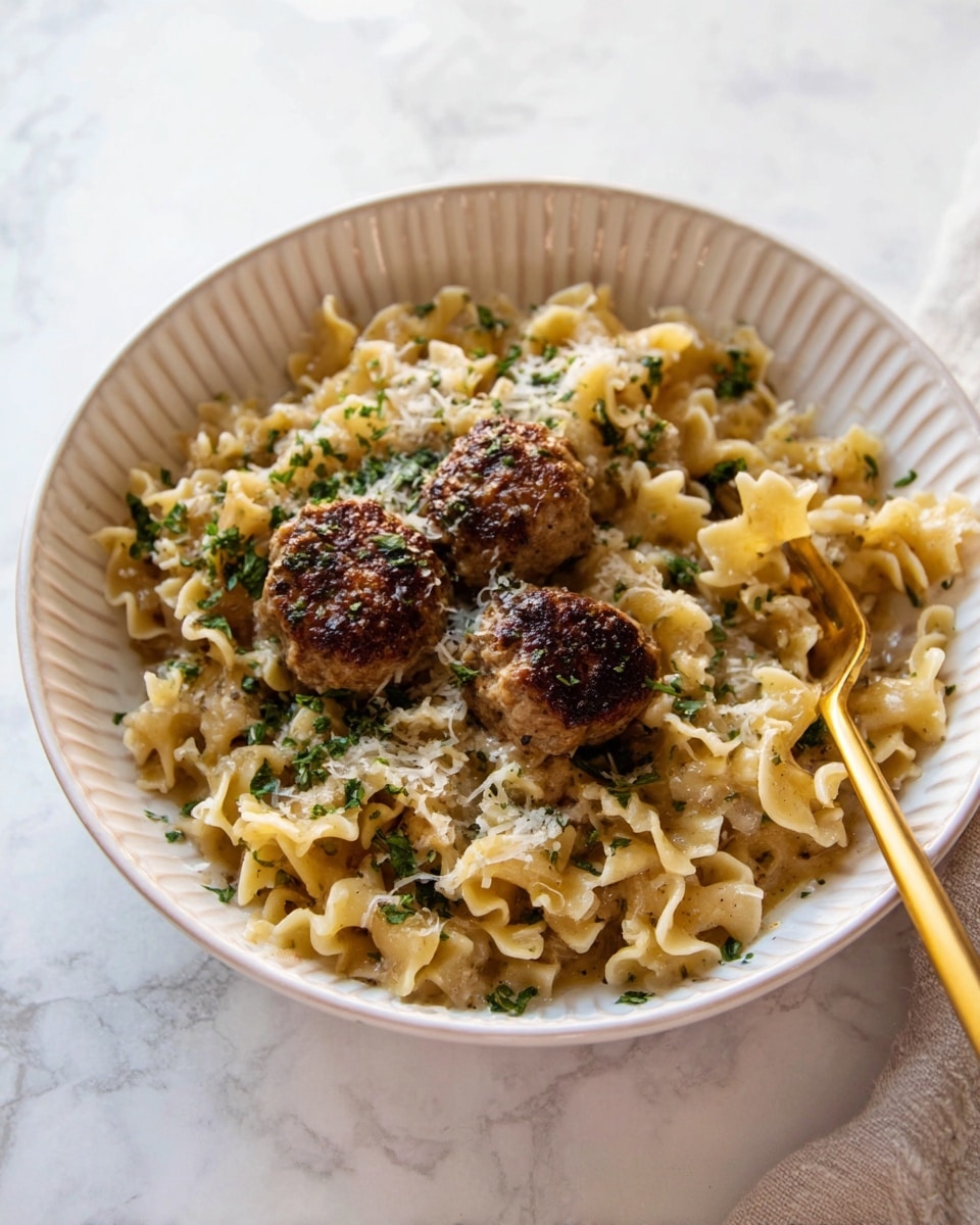 A white ribbed bowl holds a dish with three browned meatballs placed near the center on top of a bed of curly-edged pasta with a light golden color. The pasta is mixed with finely chopped green herbs and sprinkled with grated cheese. A gold fork rests on the right side of the bowl, partially submerged in the pasta. The bowl is set on a white marbled surface. photo taken with an iphone --ar 4:5 --v 7