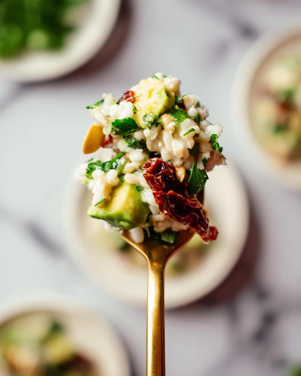 A gold spoon holds a bite of a mixed dish with three clear layers: white fluffy grains at the base, bright green avocado chunks and leafy parsley on top, and small dark brown sun-dried tomato pieces scattered throughout. The layers show a mix of rough and soft textures with the grains looking light and puffy, the avocado smooth and creamy, and the herbs fresh and leafy. The spoon is lifted above a blurred background of white marbled surface with hints of white plates and green parsley. photo taken with an iphone --ar 4:5 --v 7