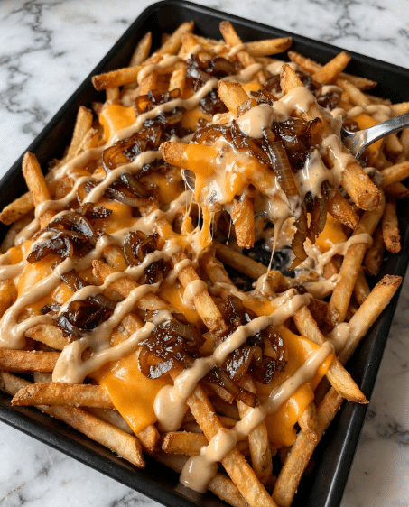 A black tray is filled with a base layer of golden brown French fries that have a crispy texture. Scattered evenly on top are caramelized onions, dark brown with a soft, slightly shiny look. There are bright orange melted cheese slices placed among the fries and onions. A creamy, light beige sauce is drizzled generously over everything, creating a smooth, glossy finish. A spoon lifts some of the layered fries, cheese, onions, and sauce. The tray sits on a white marbled surface. photo taken with an iphone --ar 4:5 --v 7