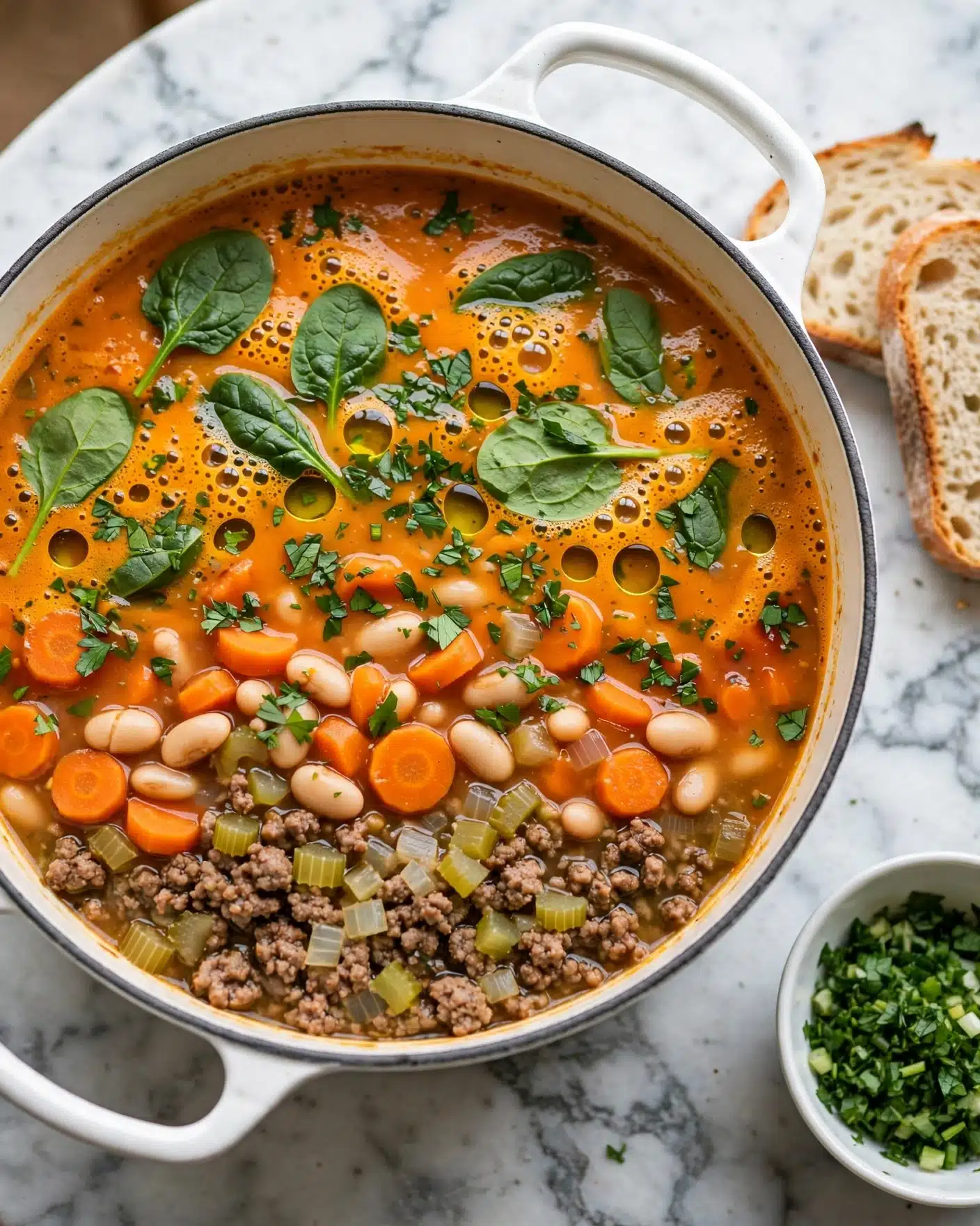 A white bowl holds creamy soup with visible layers including white beans, ground meat, green leafy spinach, orange carrot slices, and diced onions all mixed in a thick light orange broth. A metal ladle lifts a portion showing these ingredients clearly, while two pieces of white bread are in the background on a white marbled surface. The soup looks hearty with bits of herbs and spices sprinkled throughout. photo taken with an iphone --ar 4:5 --v 7